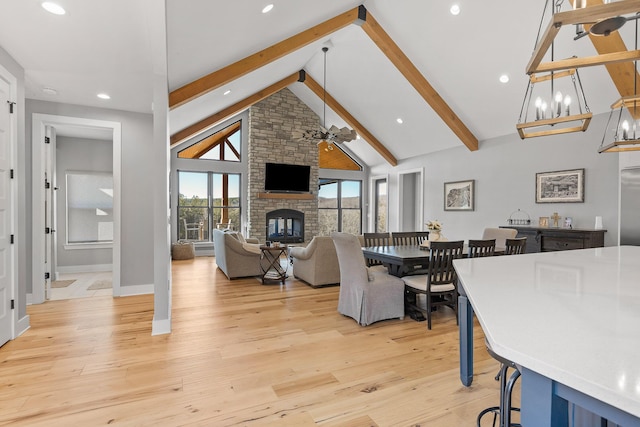 dining space with beamed ceiling, a fireplace, light hardwood / wood-style floors, and high vaulted ceiling