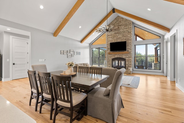 dining area with ceiling fan, high vaulted ceiling, a fireplace, light hardwood / wood-style floors, and beamed ceiling