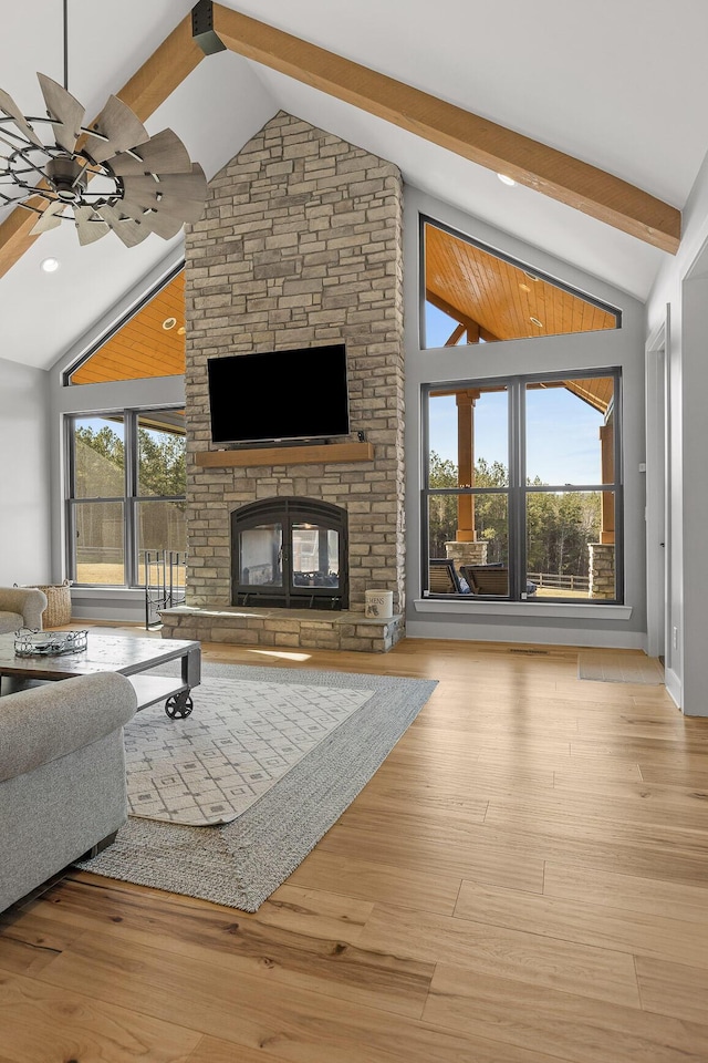 living room featuring high vaulted ceiling, light wood-type flooring, a multi sided fireplace, ceiling fan, and beam ceiling