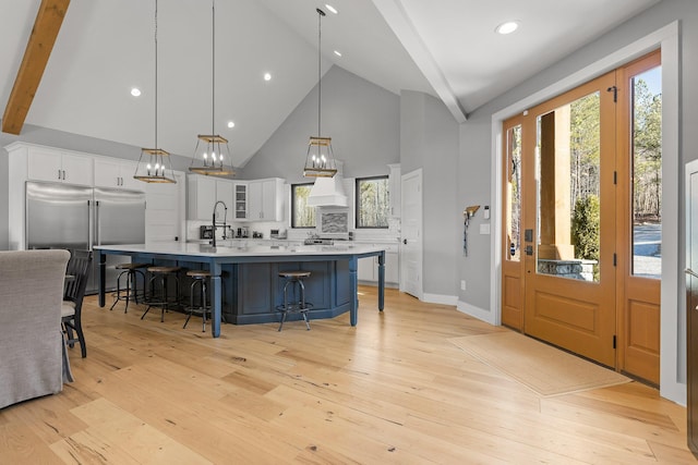 kitchen with premium range hood, a breakfast bar area, decorative light fixtures, appliances with stainless steel finishes, and white cabinets