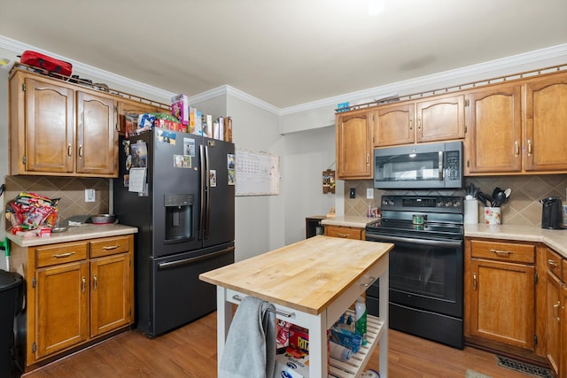 kitchen with tasteful backsplash, ornamental molding, black range with electric stovetop, and refrigerator with ice dispenser