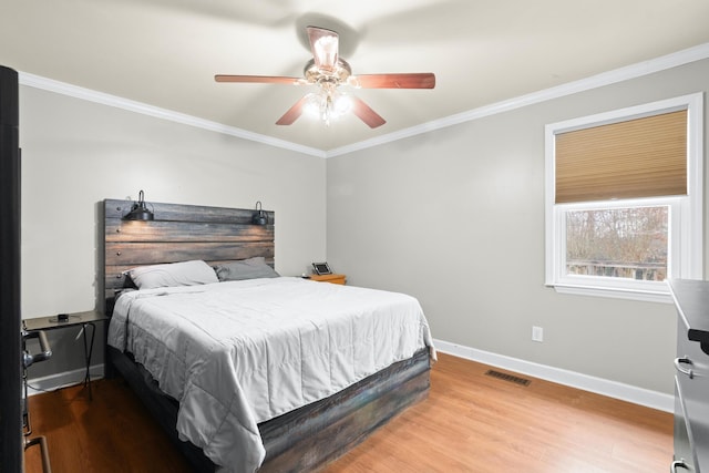 bedroom with hardwood / wood-style floors, ornamental molding, and ceiling fan