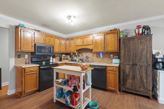 kitchen with sink, ornamental molding, hardwood / wood-style floors, decorative backsplash, and black appliances