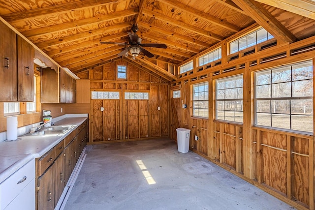 kitchen with lofted ceiling, sink, wooden walls, and ceiling fan