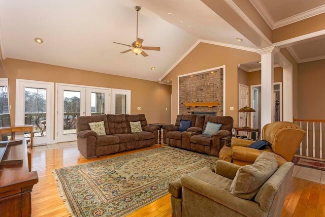 living room with crown molding, light hardwood / wood-style floors, a brick fireplace, and ornate columns