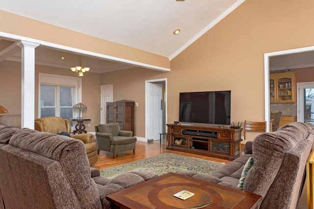 living room with lofted ceiling, ornate columns, crown molding, a chandelier, and hardwood / wood-style flooring