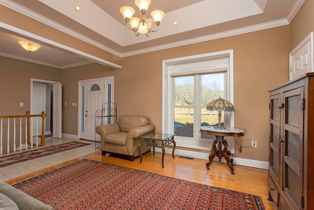 living area with an inviting chandelier, crown molding, light hardwood / wood-style flooring, and a raised ceiling