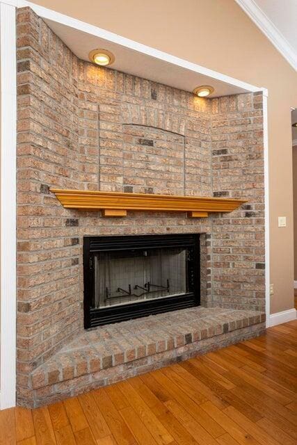 room details with a brick fireplace, hardwood / wood-style flooring, and ornamental molding