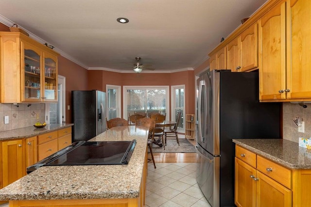 kitchen with crown molding, a center island, stainless steel fridge with ice dispenser, light tile patterned floors, and light stone countertops