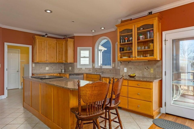 kitchen with light stone countertops, crown molding, a kitchen breakfast bar, and backsplash