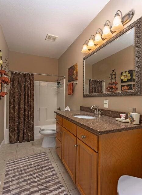 full bathroom featuring vanity, shower / bath combo, tile patterned floors, and toilet