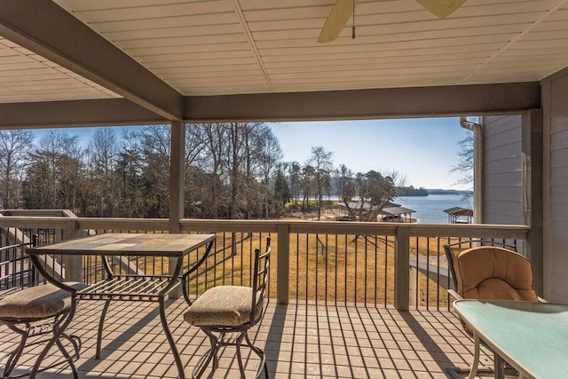 wooden deck with ceiling fan and a water view