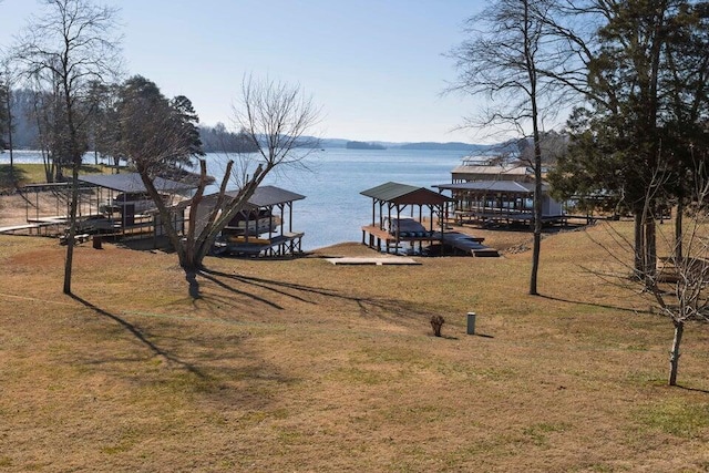 view of dock with a water view and a lawn