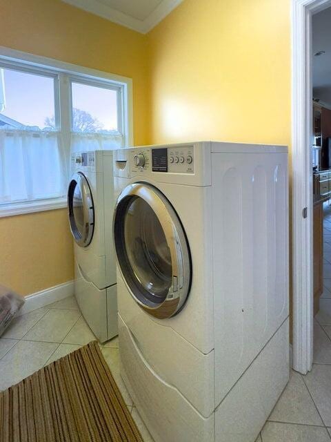 laundry area with light tile patterned flooring, crown molding, and washing machine and dryer