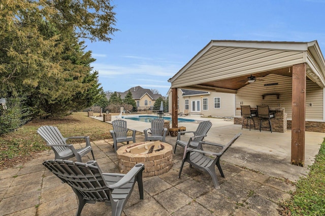 view of patio featuring exterior bar, an outbuilding, ceiling fan, and an outdoor fire pit