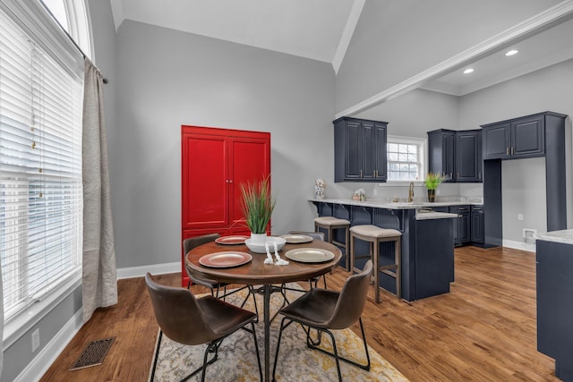 dining area with crown molding, high vaulted ceiling, dark hardwood / wood-style flooring, and sink