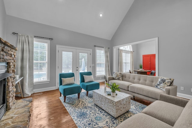 living room with french doors, high vaulted ceiling, a fireplace, and hardwood / wood-style floors