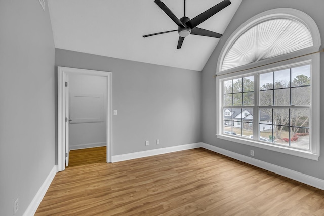 unfurnished bedroom with lofted ceiling, a walk in closet, ceiling fan, and light wood-type flooring