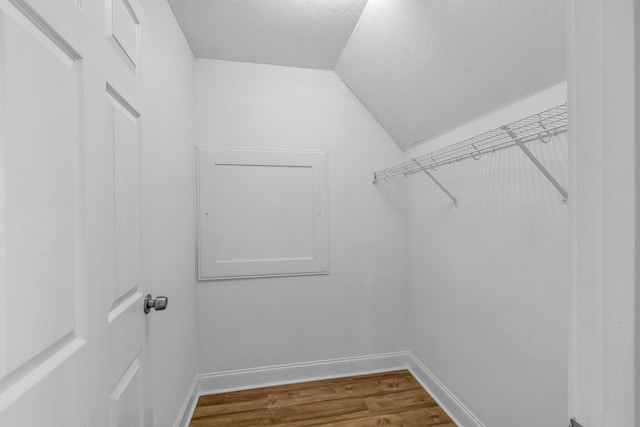 walk in closet with hardwood / wood-style flooring and vaulted ceiling