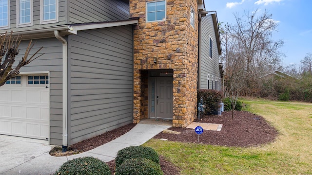 entrance to property featuring a yard and a garage