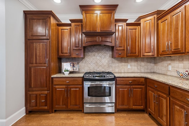 kitchen with gas stove, crown molding, and light hardwood / wood-style flooring