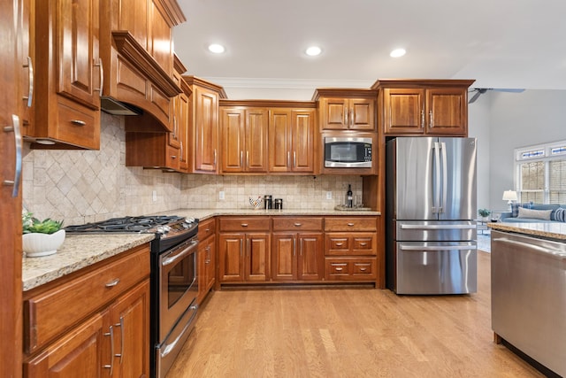 kitchen featuring light stone counters, appliances with stainless steel finishes, light hardwood / wood-style flooring, and backsplash