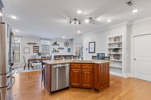 kitchen featuring appliances with stainless steel finishes, sink, light hardwood / wood-style floors, and a kitchen island with sink