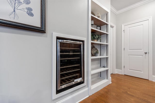 interior space featuring hardwood / wood-style floors, crown molding, and beverage cooler