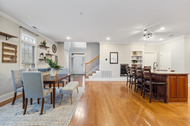 dining area featuring sink, ornamental molding, and light wood-type flooring