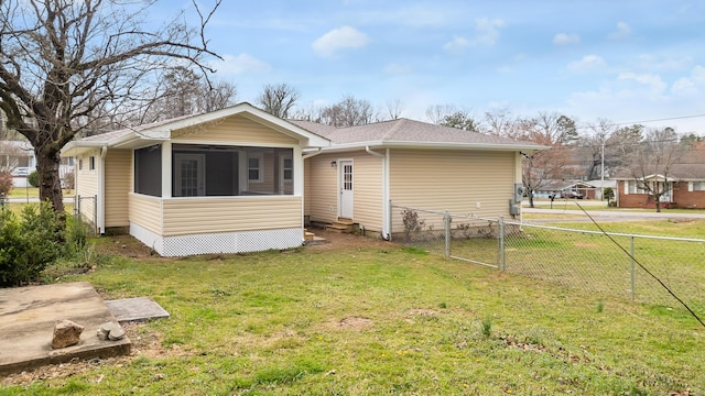 rear view of property featuring a shingled roof, fence, entry steps, a yard, and a sunroom