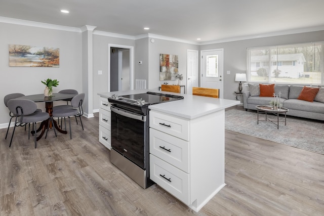 kitchen with light wood finished floors, a kitchen island, ornamental molding, stainless steel range with electric cooktop, and white cabinetry