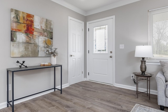 foyer entrance featuring baseboards, wood finished floors, and crown molding