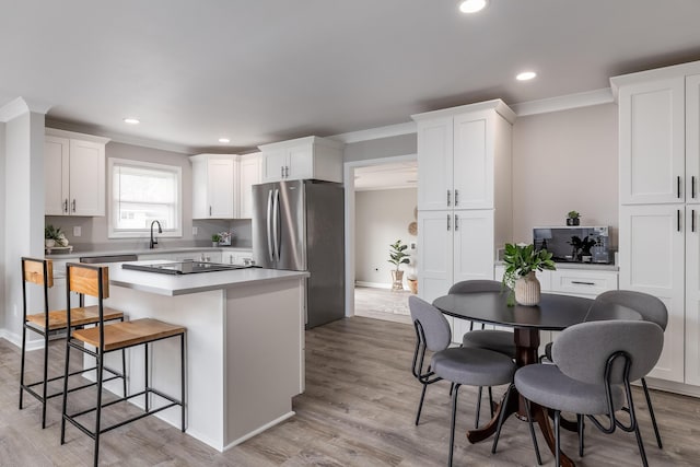 kitchen featuring light wood finished floors, freestanding refrigerator, a sink, white cabinetry, and a center island