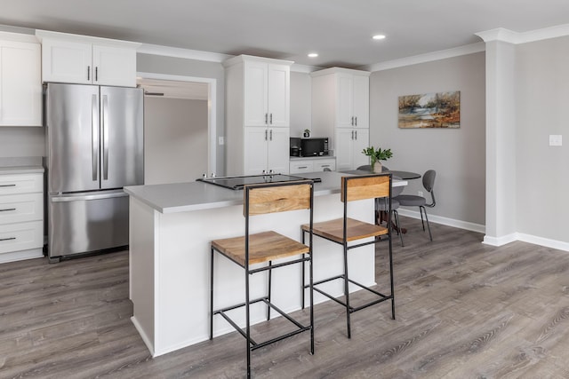 kitchen with ornamental molding, wood finished floors, freestanding refrigerator, and black microwave