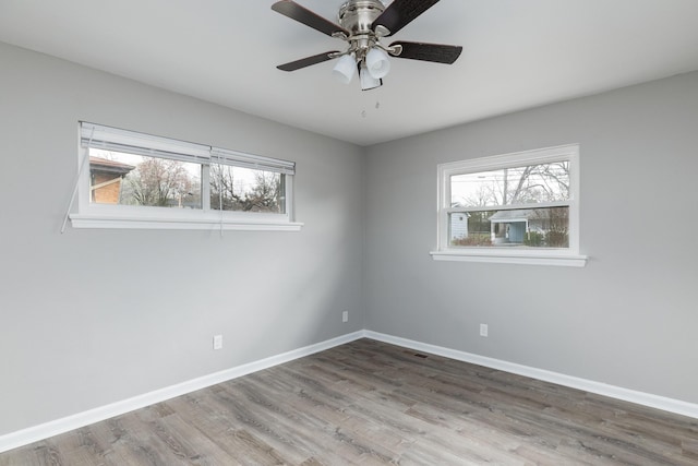 empty room with a ceiling fan, baseboards, and wood finished floors