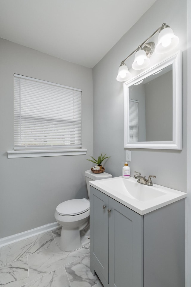 bathroom featuring baseboards, toilet, marble finish floor, and vanity