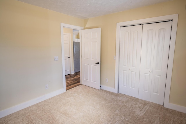 unfurnished bedroom featuring light carpet, a closet, and a textured ceiling