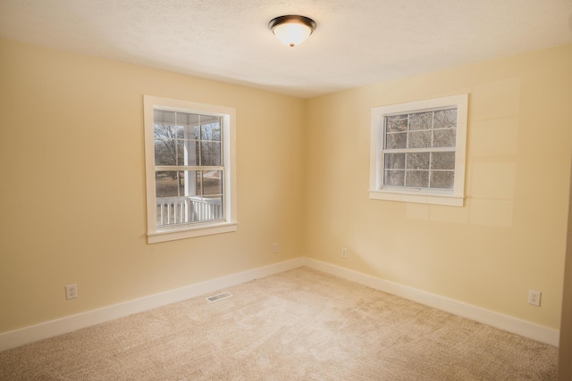 carpeted empty room featuring a textured ceiling