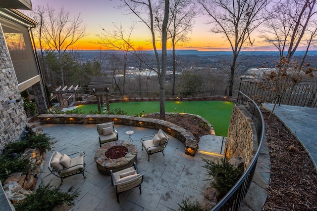 patio terrace at dusk with an outdoor fire pit and a yard