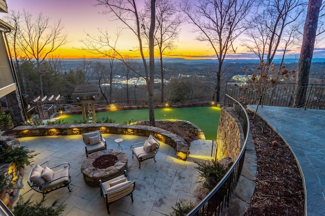 patio terrace at dusk featuring a yard and an outdoor fire pit