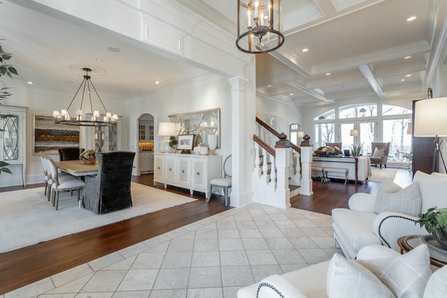 living room with an inviting chandelier, beam ceiling, coffered ceiling, ornamental molding, and light tile patterned flooring