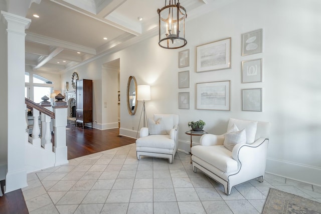 living area featuring coffered ceiling, a notable chandelier, ornamental molding, beamed ceiling, and ornate columns