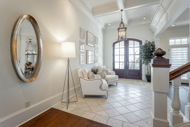 foyer with beamed ceiling, coffered ceiling, light tile patterned floors, crown molding, and french doors