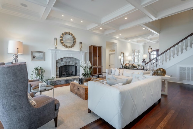 living room with coffered ceiling, hardwood / wood-style floors, a stone fireplace, and beamed ceiling