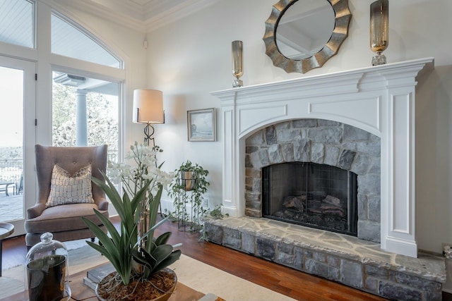 living area featuring hardwood / wood-style flooring, a fireplace, and crown molding