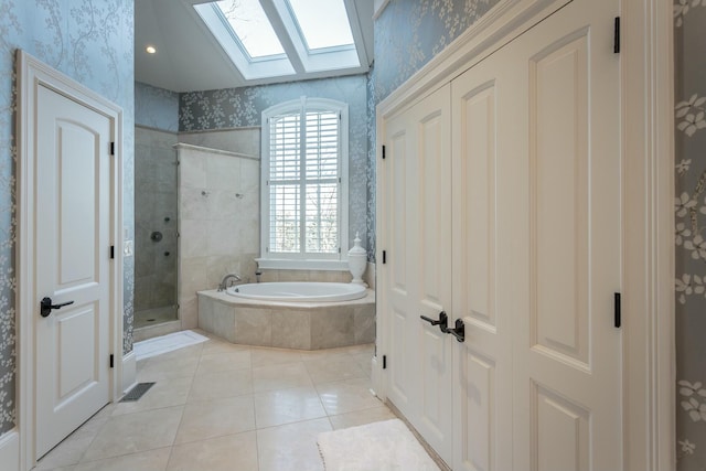 bathroom with shower with separate bathtub, a skylight, and tile patterned flooring