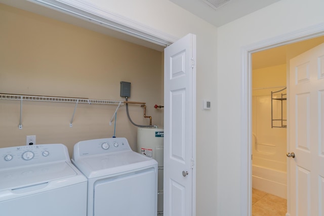 washroom featuring light tile patterned floors, water heater, and washing machine and clothes dryer