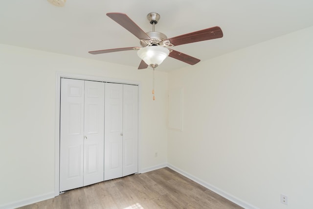 unfurnished bedroom featuring ceiling fan, a closet, and light wood-type flooring