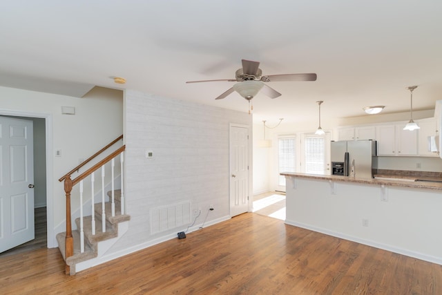 kitchen featuring light hardwood / wood-style flooring, a breakfast bar, white cabinets, stainless steel fridge with ice dispenser, and kitchen peninsula