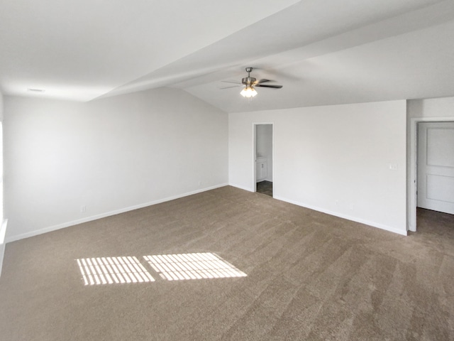 spare room with vaulted ceiling, ceiling fan, and dark carpet